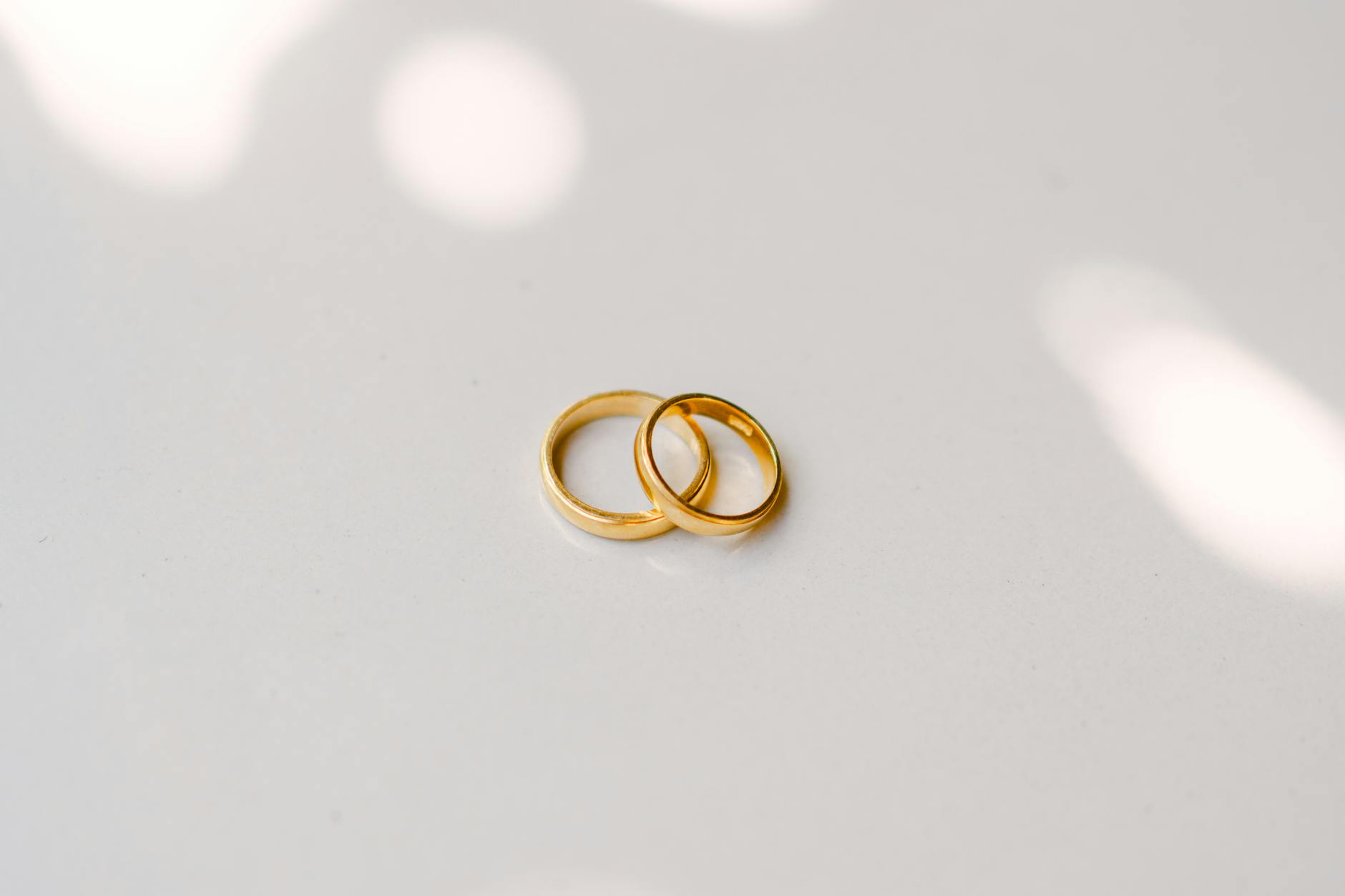 Minimalist composition of two gold wedding rings with soft lighting, ideal for wedding themes.