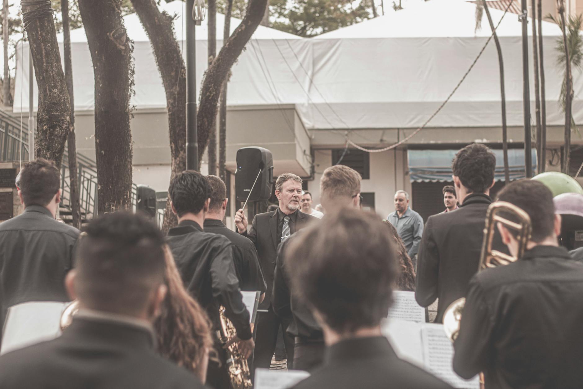 Outdoor orchestra directed by a conductor with musicians playing brass instruments.