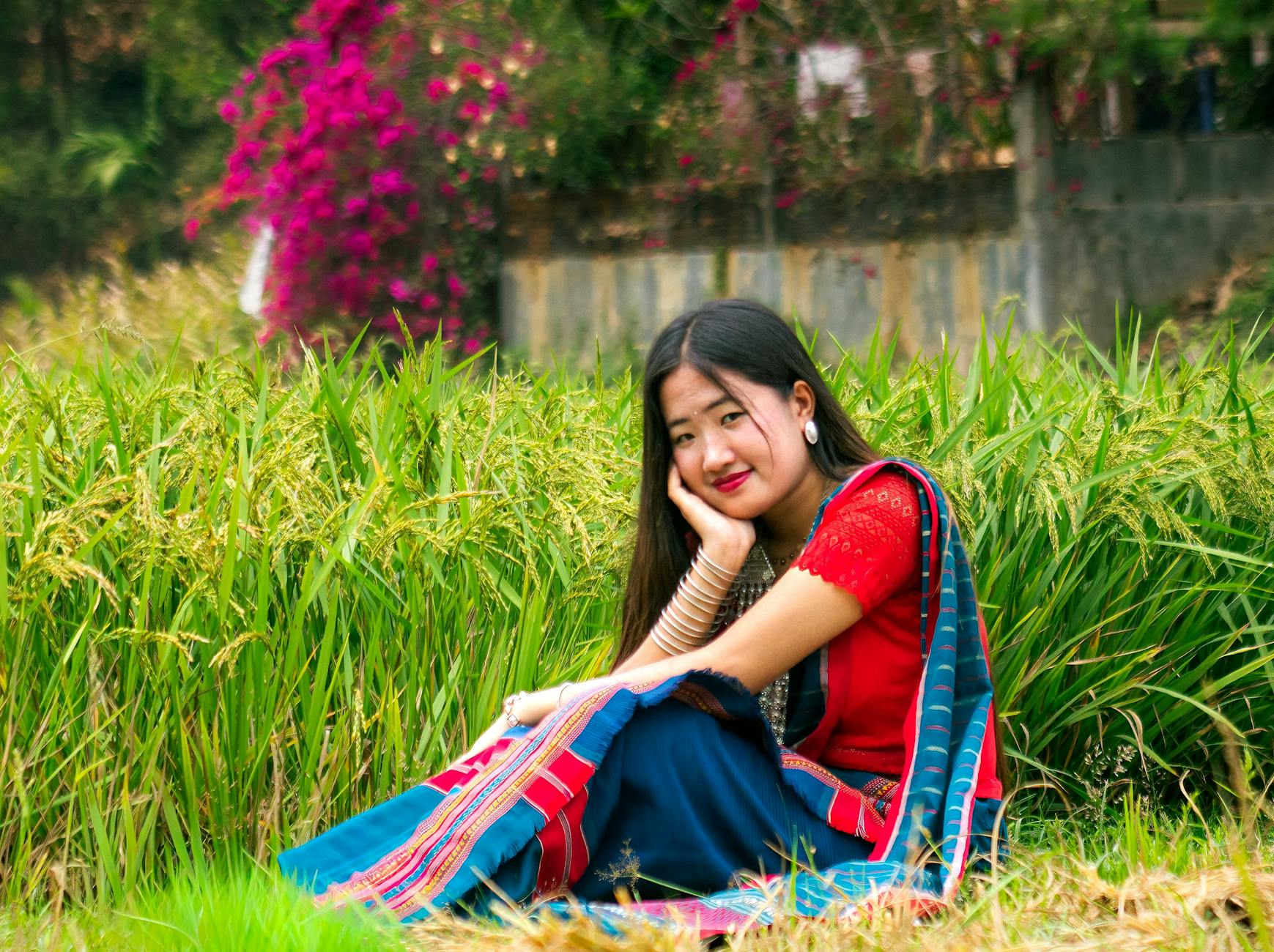 Portrait of a Chakma woman in traditional attire sitting amidst nature in Rangamati, Bangladesh.