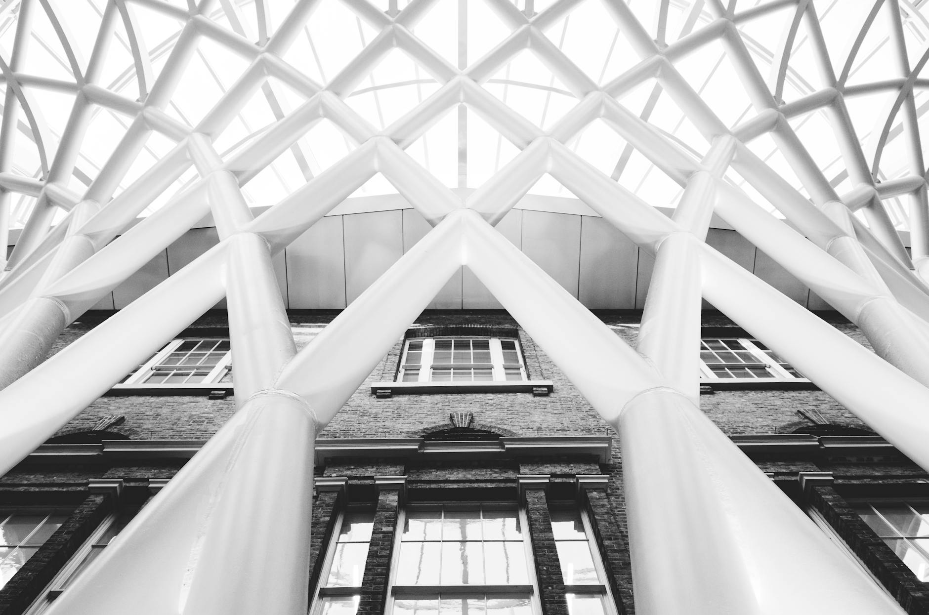 Black and white photo of the intricate modern roof structure at King's Cross Station in London, England.