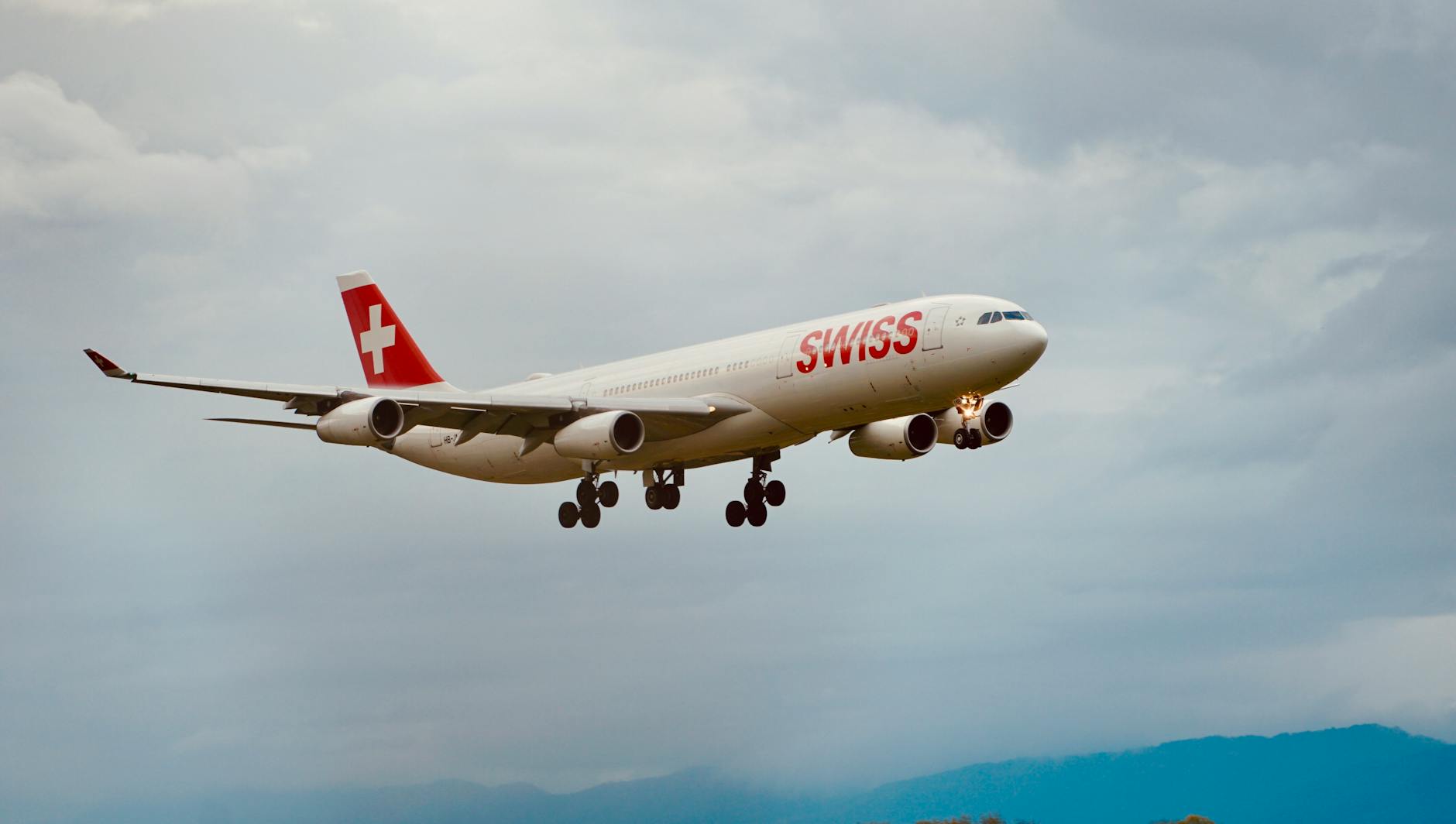 Swiss airplane flying against a backdrop of cloudy sky, showcasing aviation and travel.
