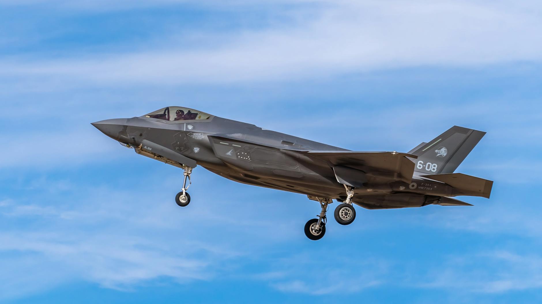 F-35 fighter jet captured mid-flight against a clear blue sky in Albacete, Spain.