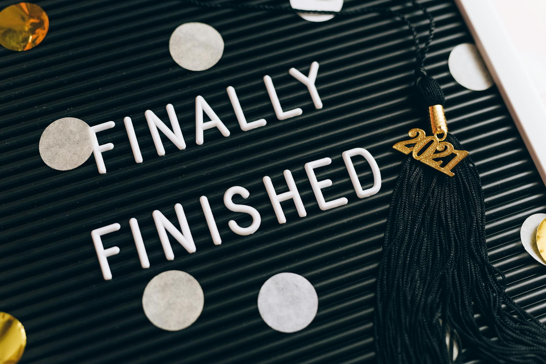 Close-up of a letter board with 'Finally Finished' text and 2021 graduation tassel.