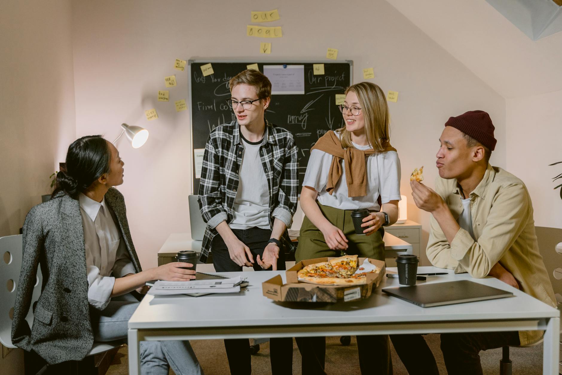 Diverse team discussing ideas over pizza in a modern office.