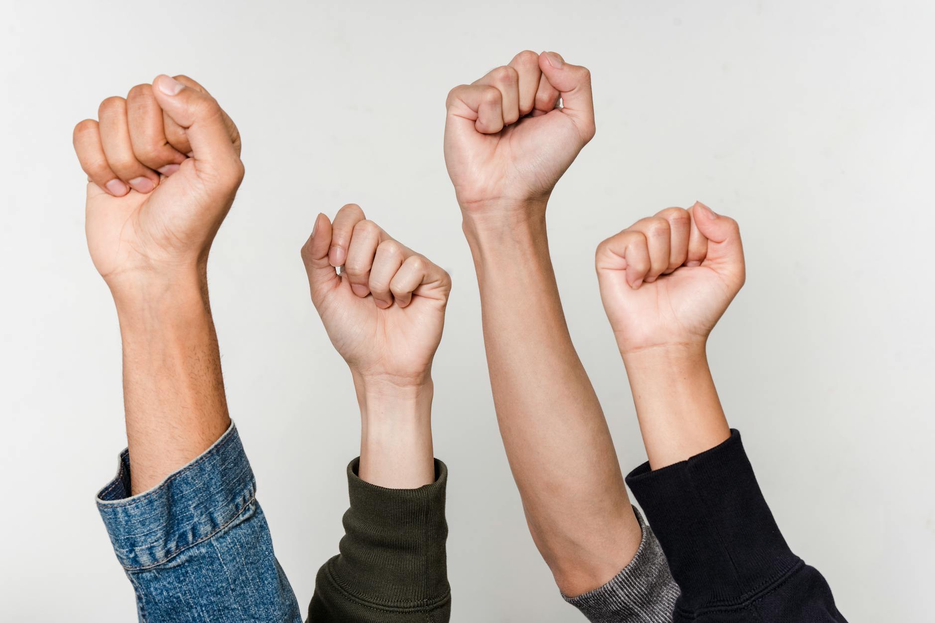 Four diverse fists raised in solidarity, symbolizing unity, triumph, and empowerment.