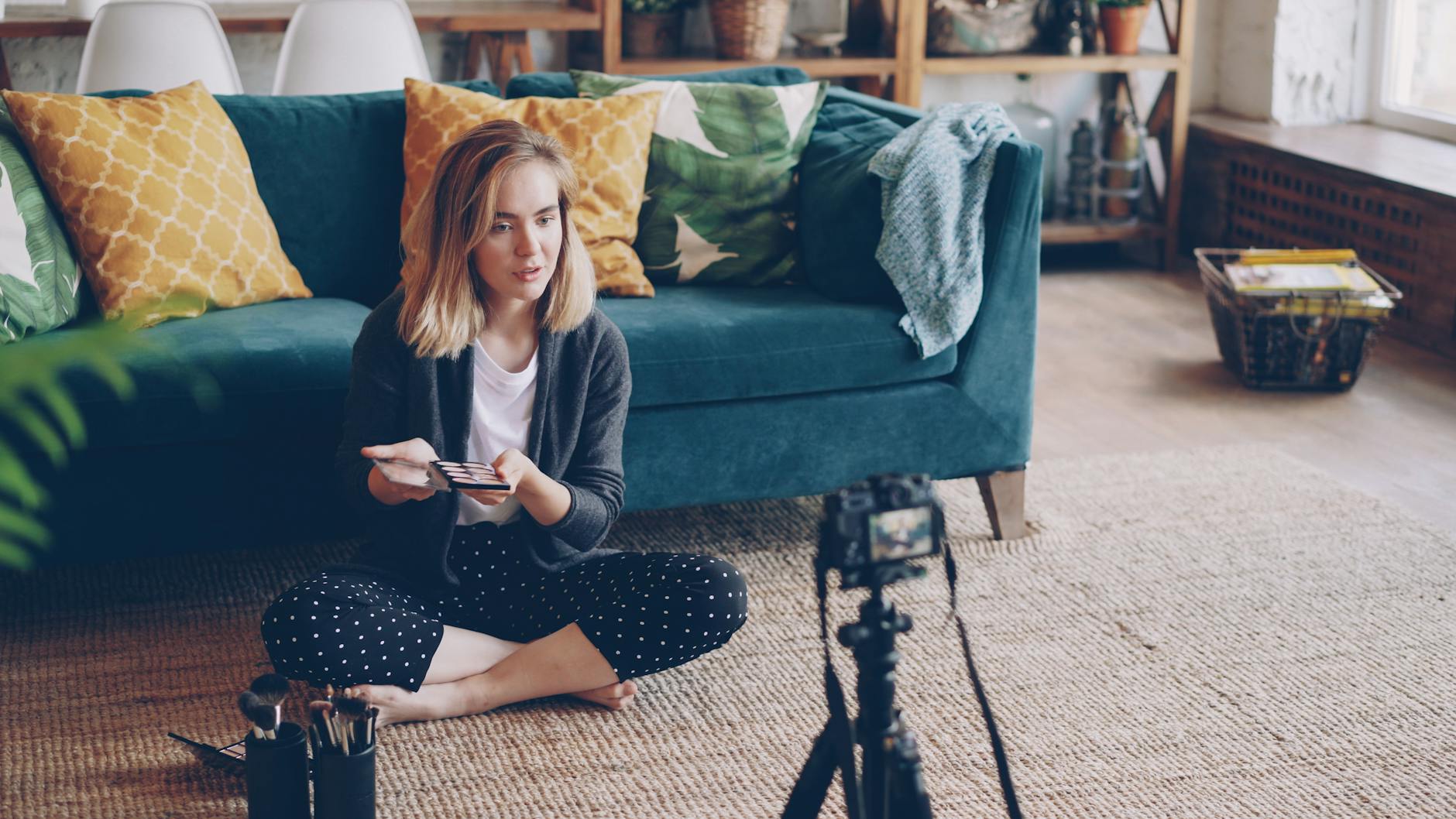 Woman recording a makeup tutorial video in a stylish, comfy living room.