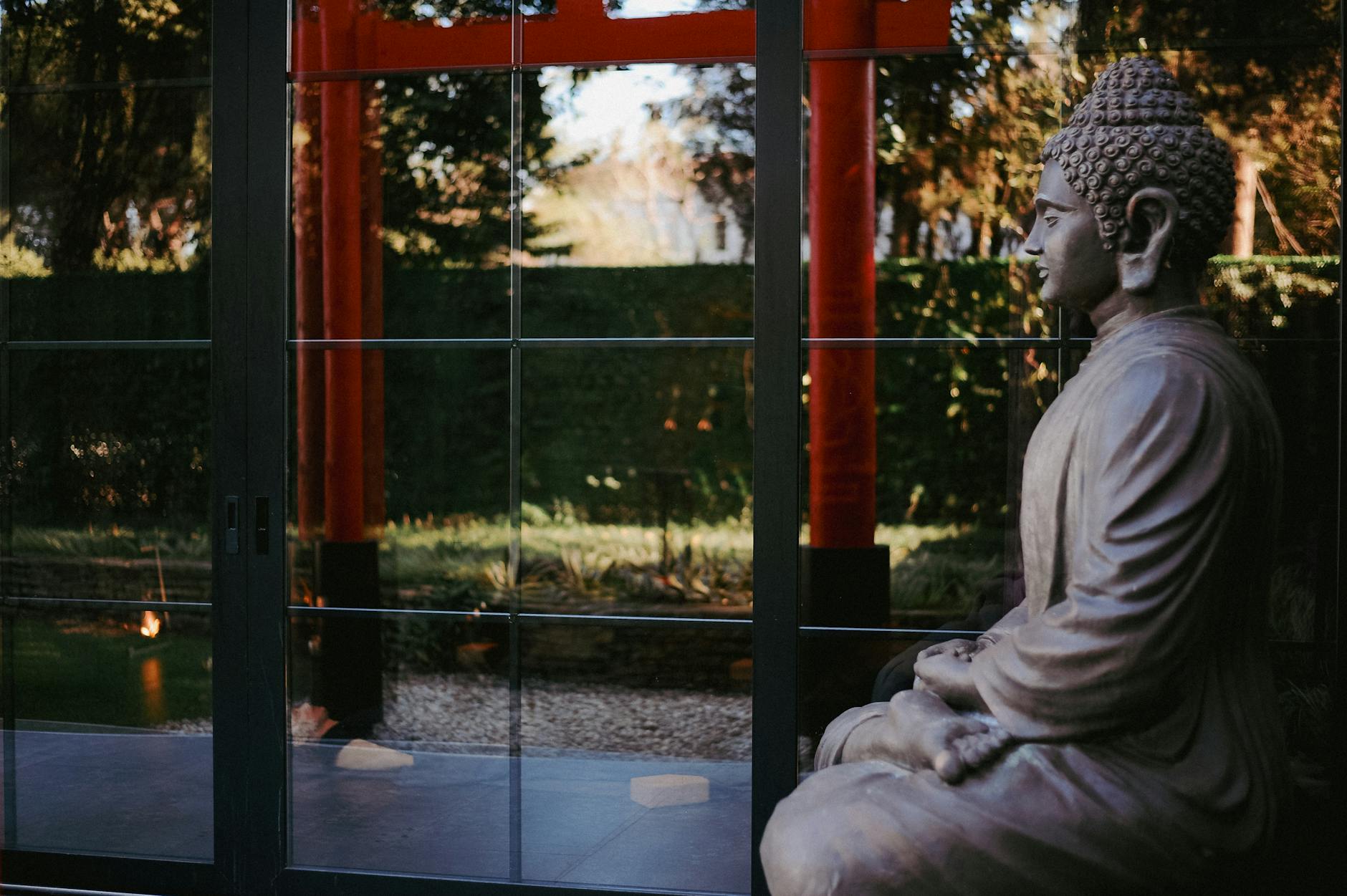 Serene Buddha statue with reflection in glass doors of a temple entrance.