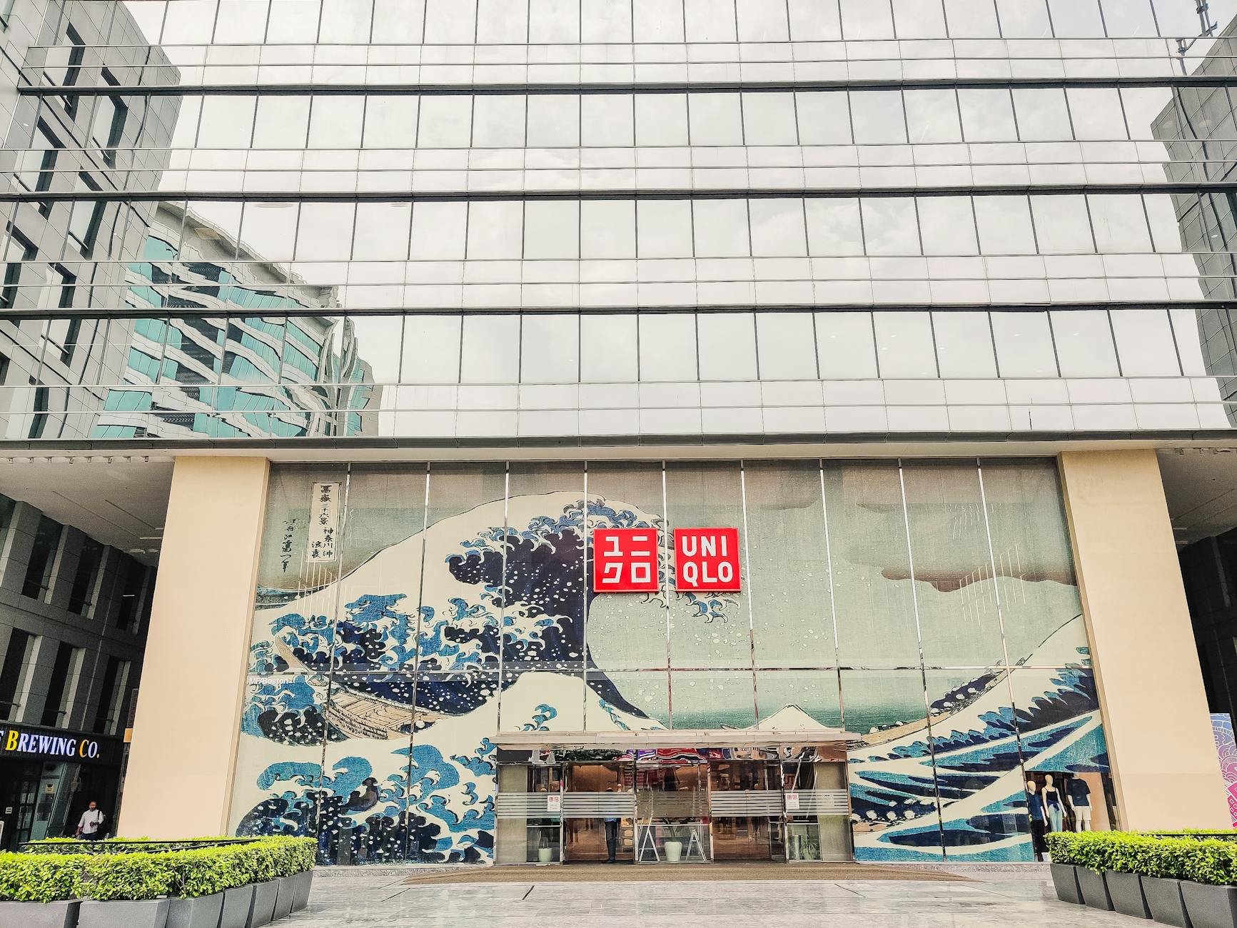 Uniqlo storefront featuring The Great Wave mural in a modern glass building facade.