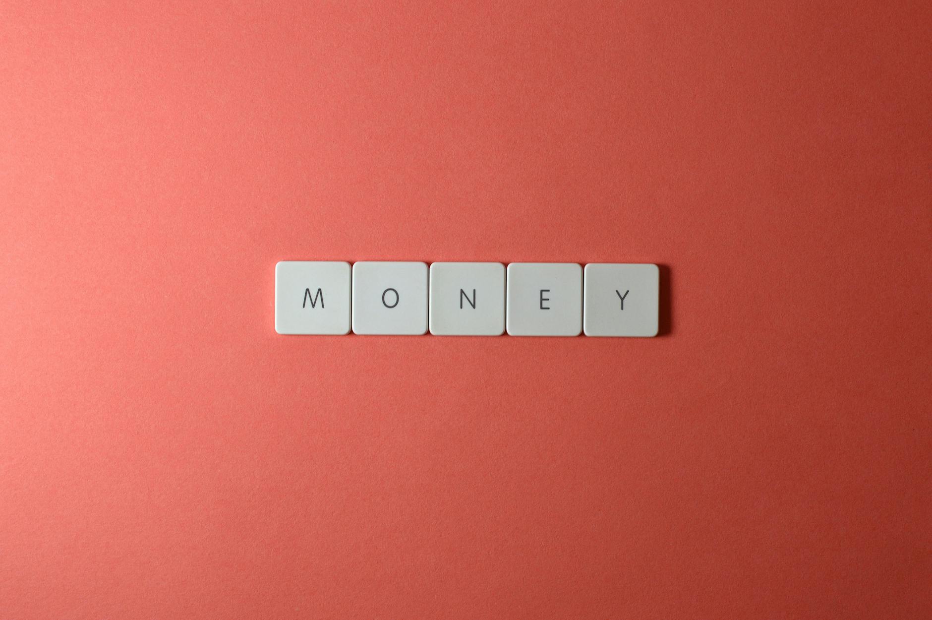 Minimalist layout showing word 'money' with letter tiles on a coral background.