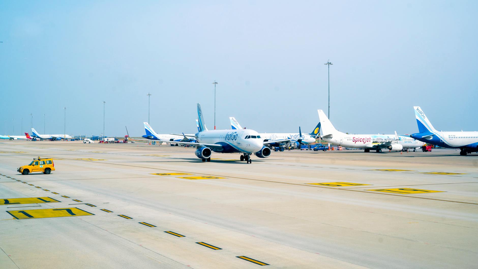 Airplanes on taxiways at a bustling airport on a clear day.