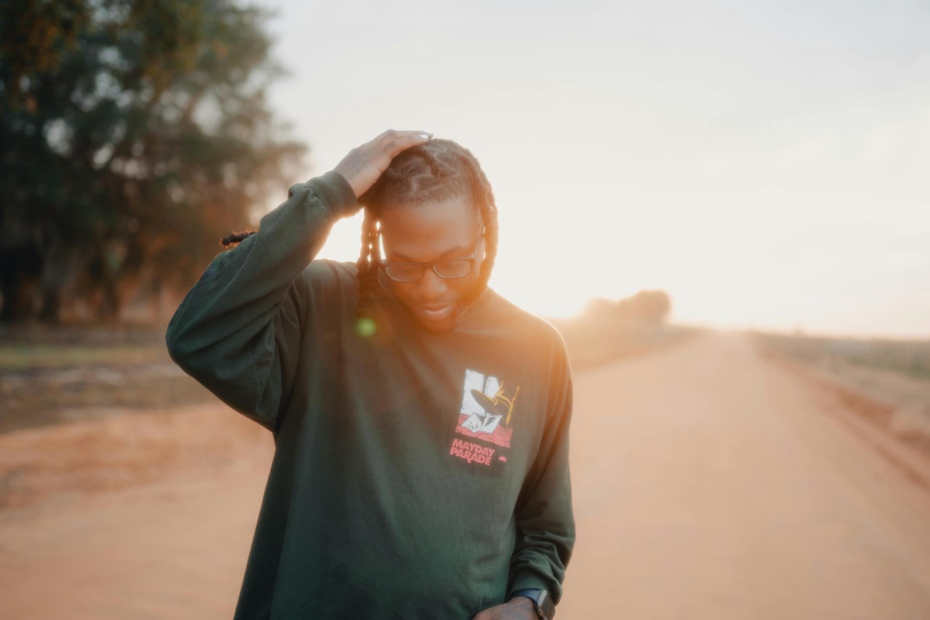Man standing on a dirt road during sunset, appearing thoughtful and serene.