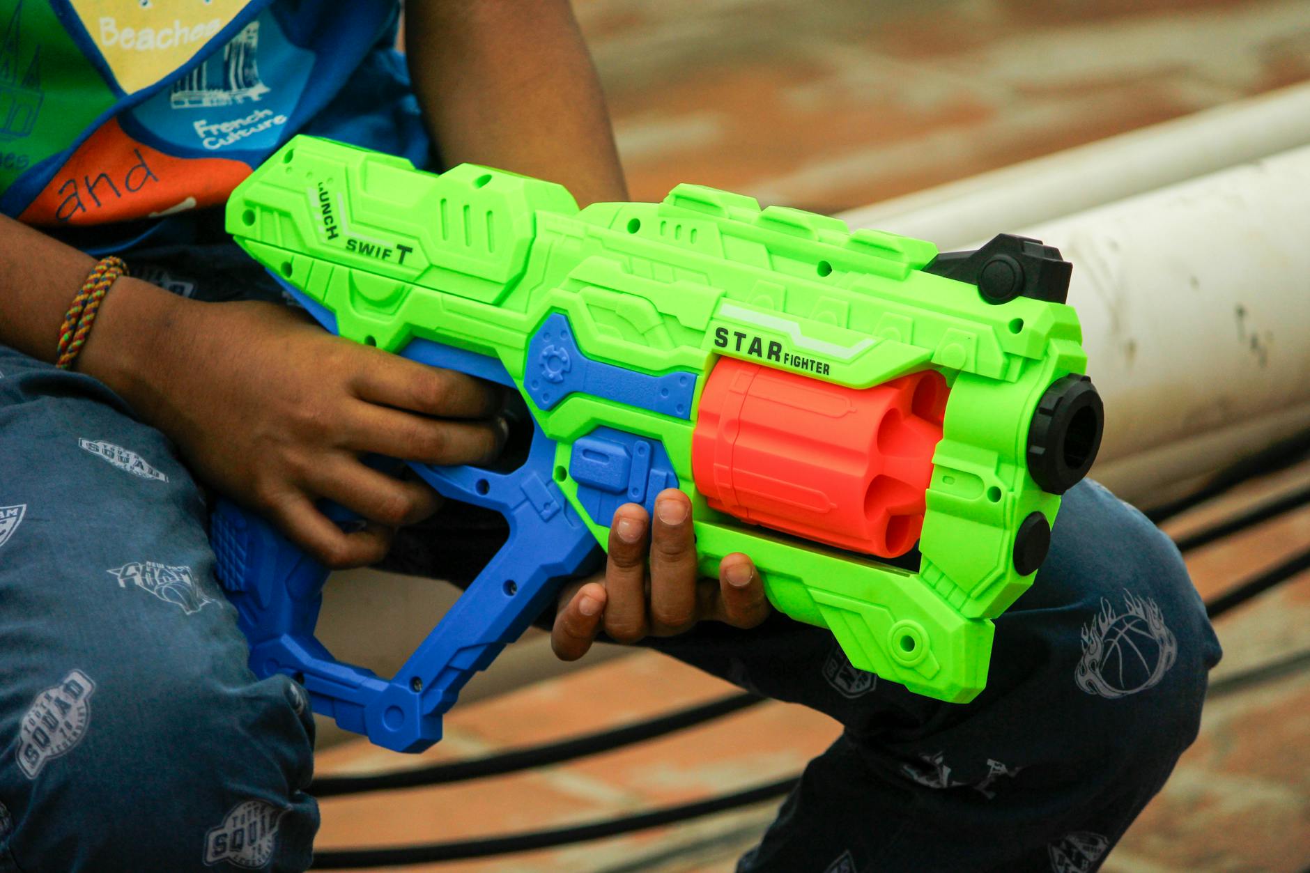 A close-up of a child holding a colorful toy gun, featuring vibrant colors and playful design.