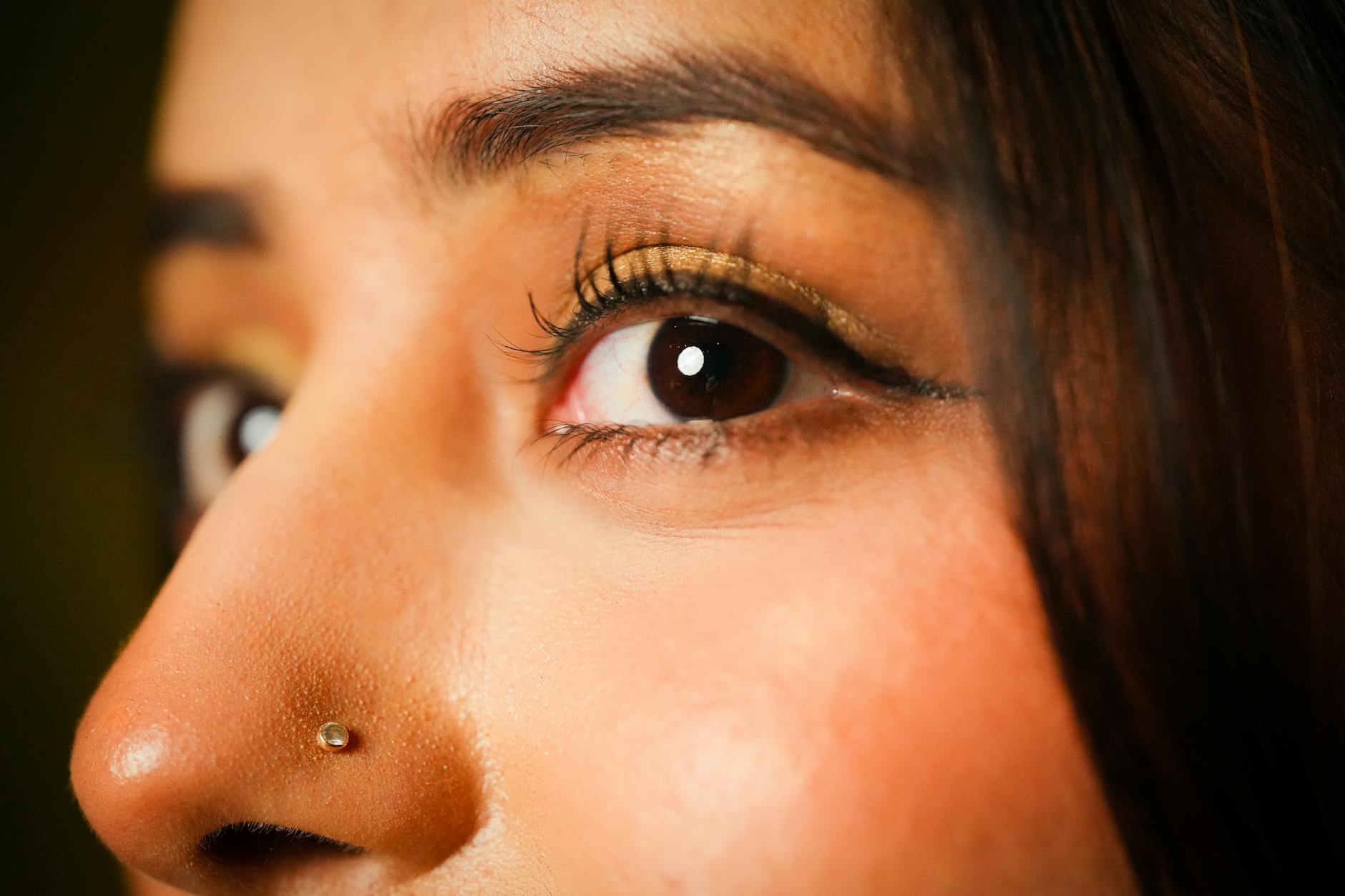 A detailed close-up of a woman's eye showcasing elegant eyeliner and gold eyeshadow.