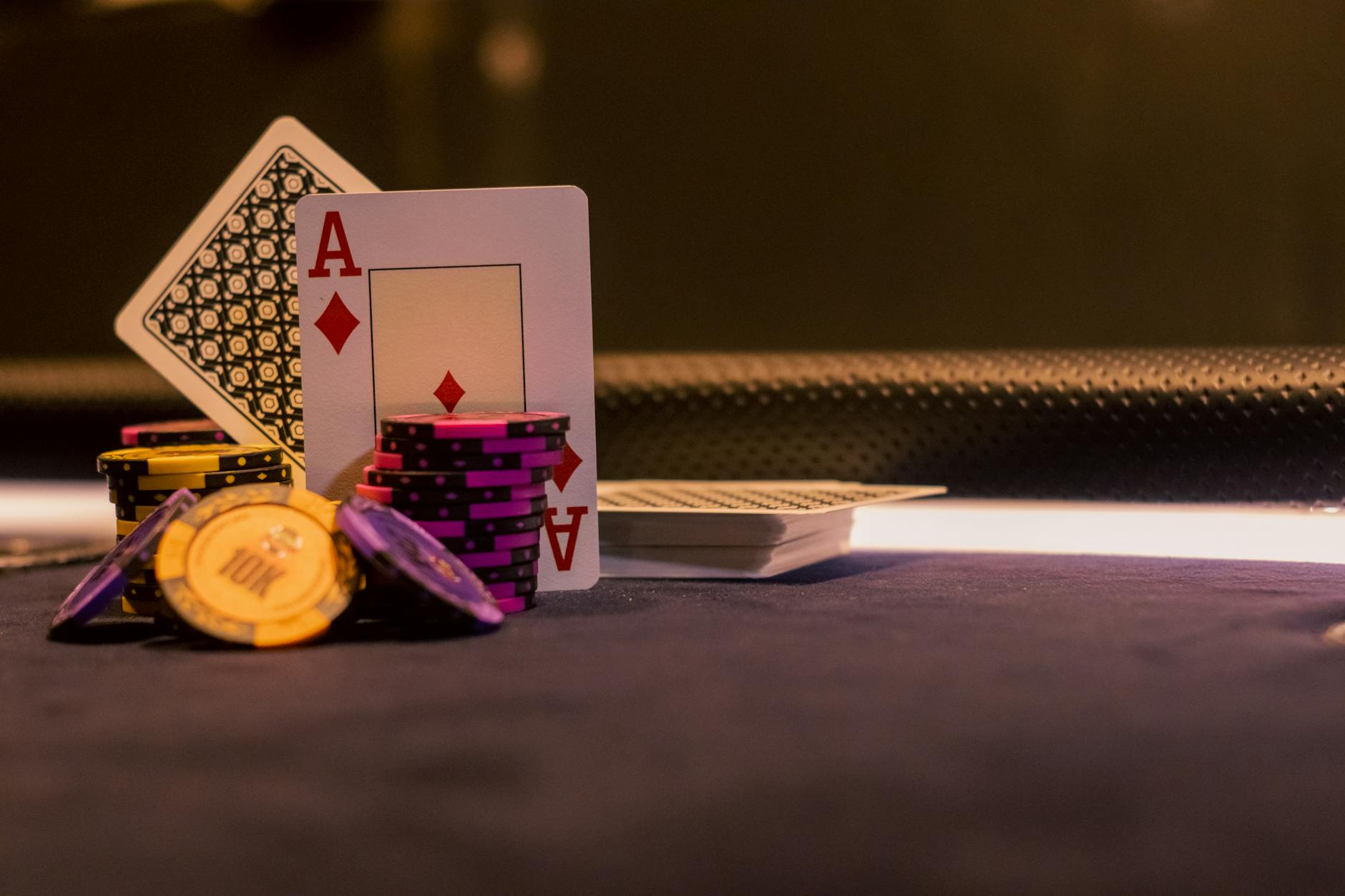 A close-up of poker chips and playing cards on a casino gaming table, highlighting Ace of Diamonds.