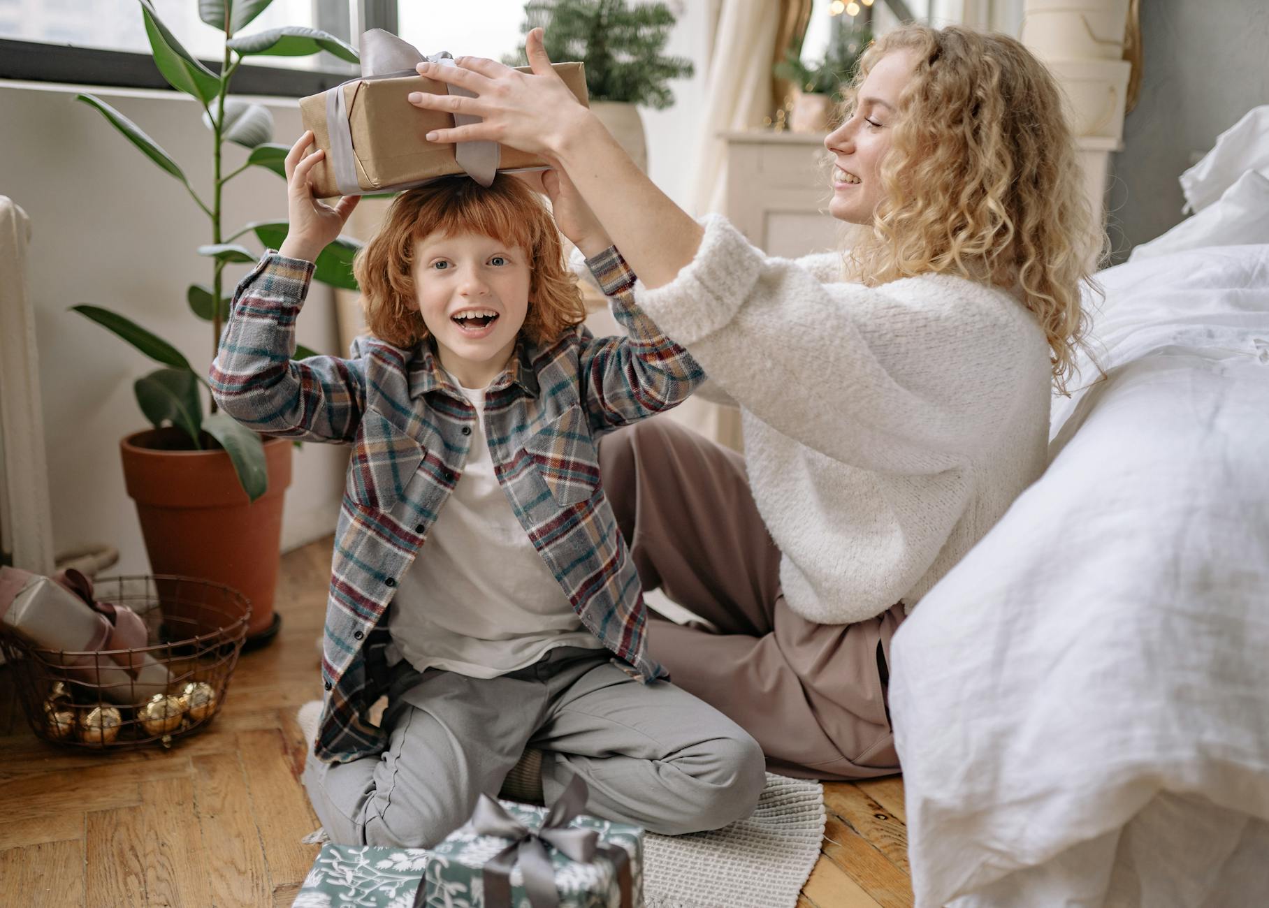 A joyful moment of a mother and son exchanging gifts during a cozy Christmas celebration indoors.