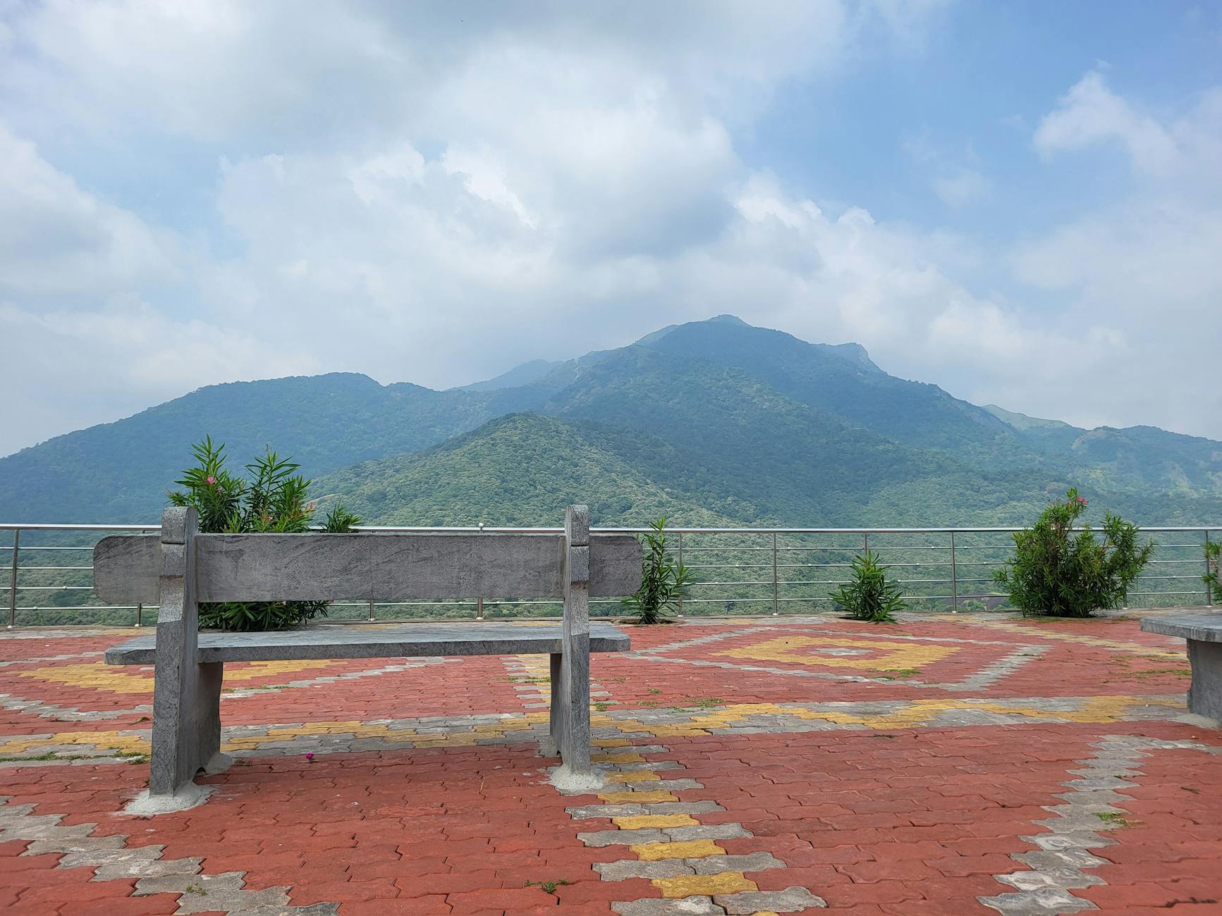Serene mountain landscape with an empty bench on a colorful terrace in Thenpothai, Tamil Nadu.