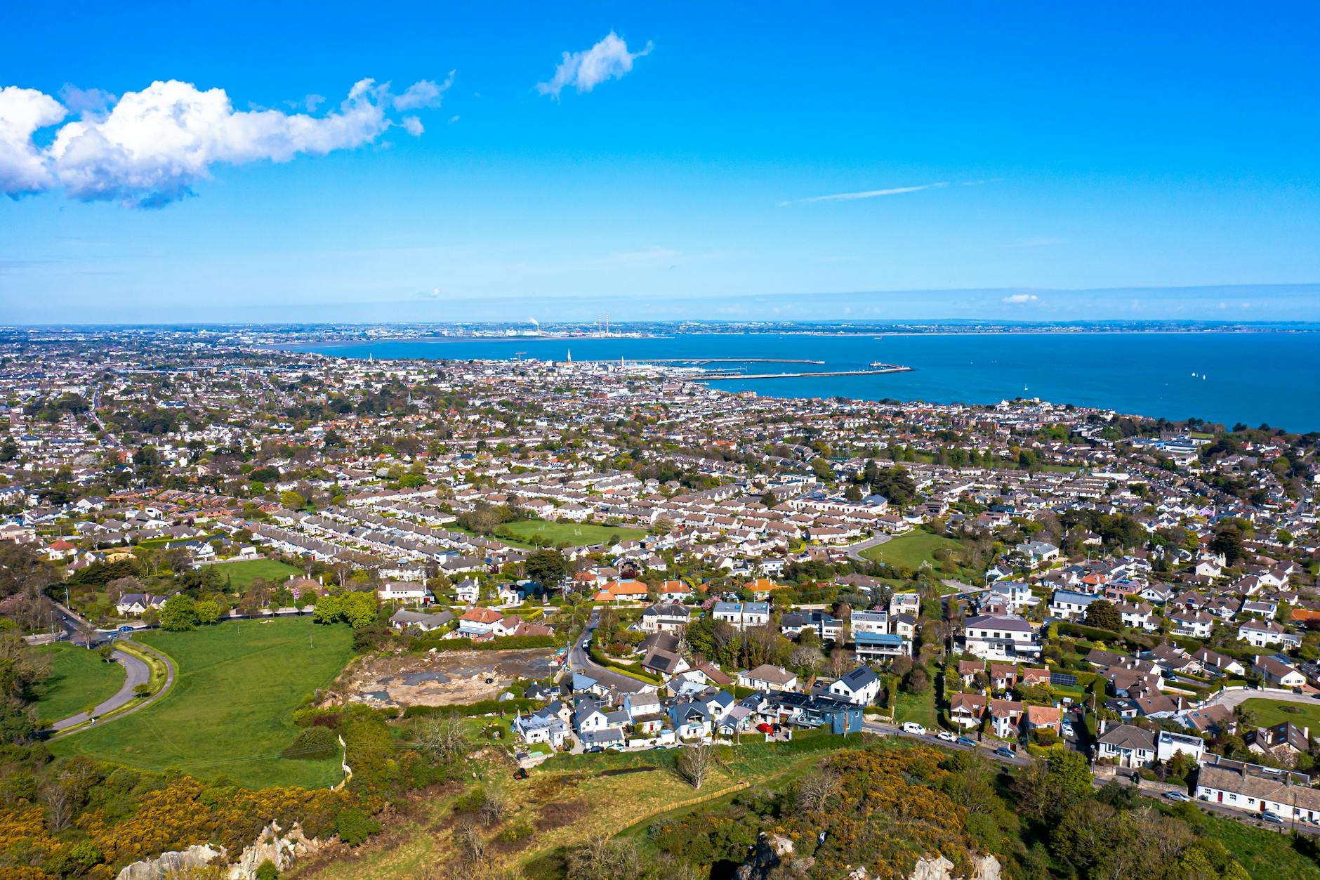 Aerial view of a coastal town with lush greenery and ocean in the background.