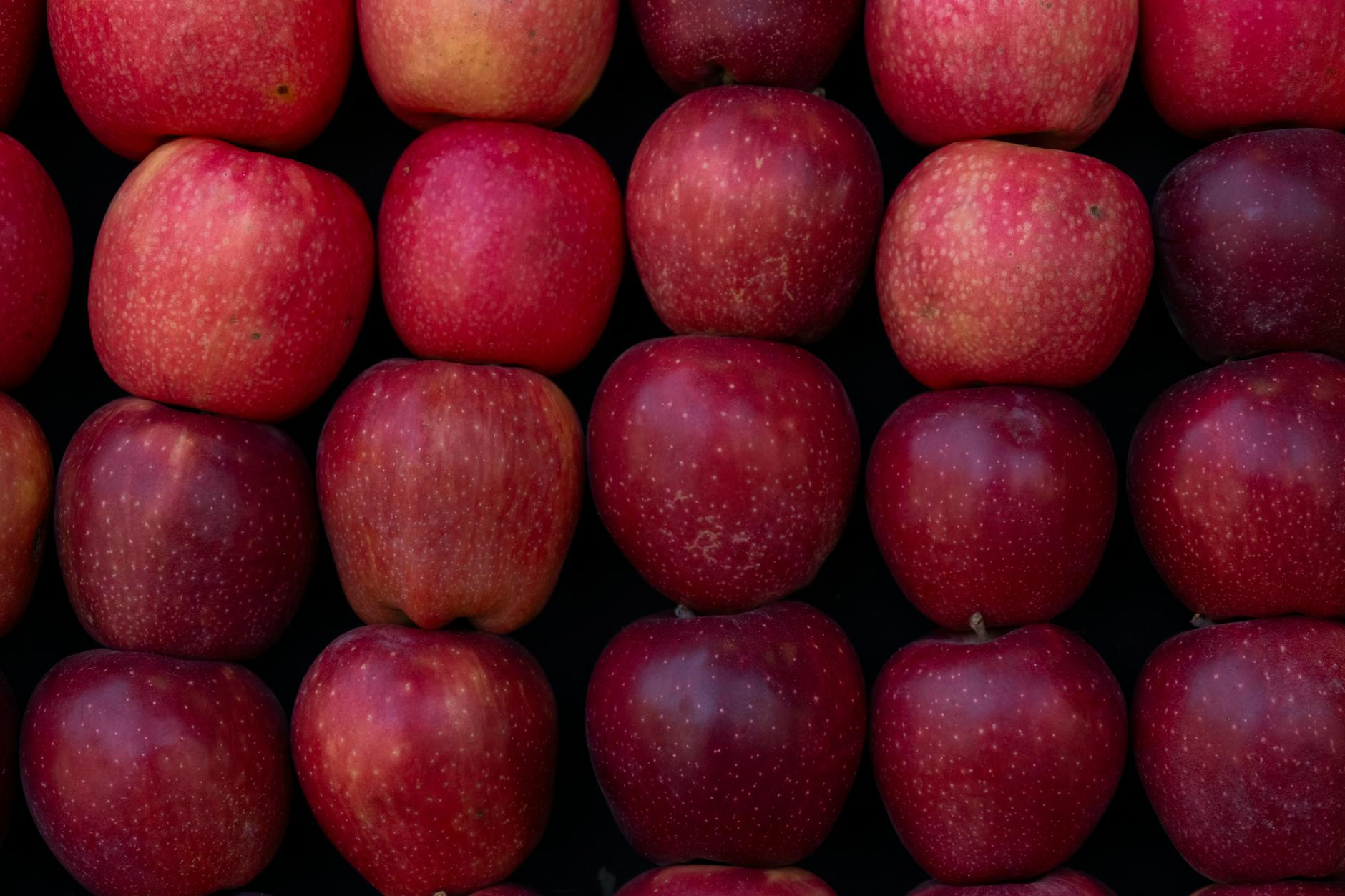 A selection of fresh organic red apples displayed neatly in a market stall, vibrant and ripe.