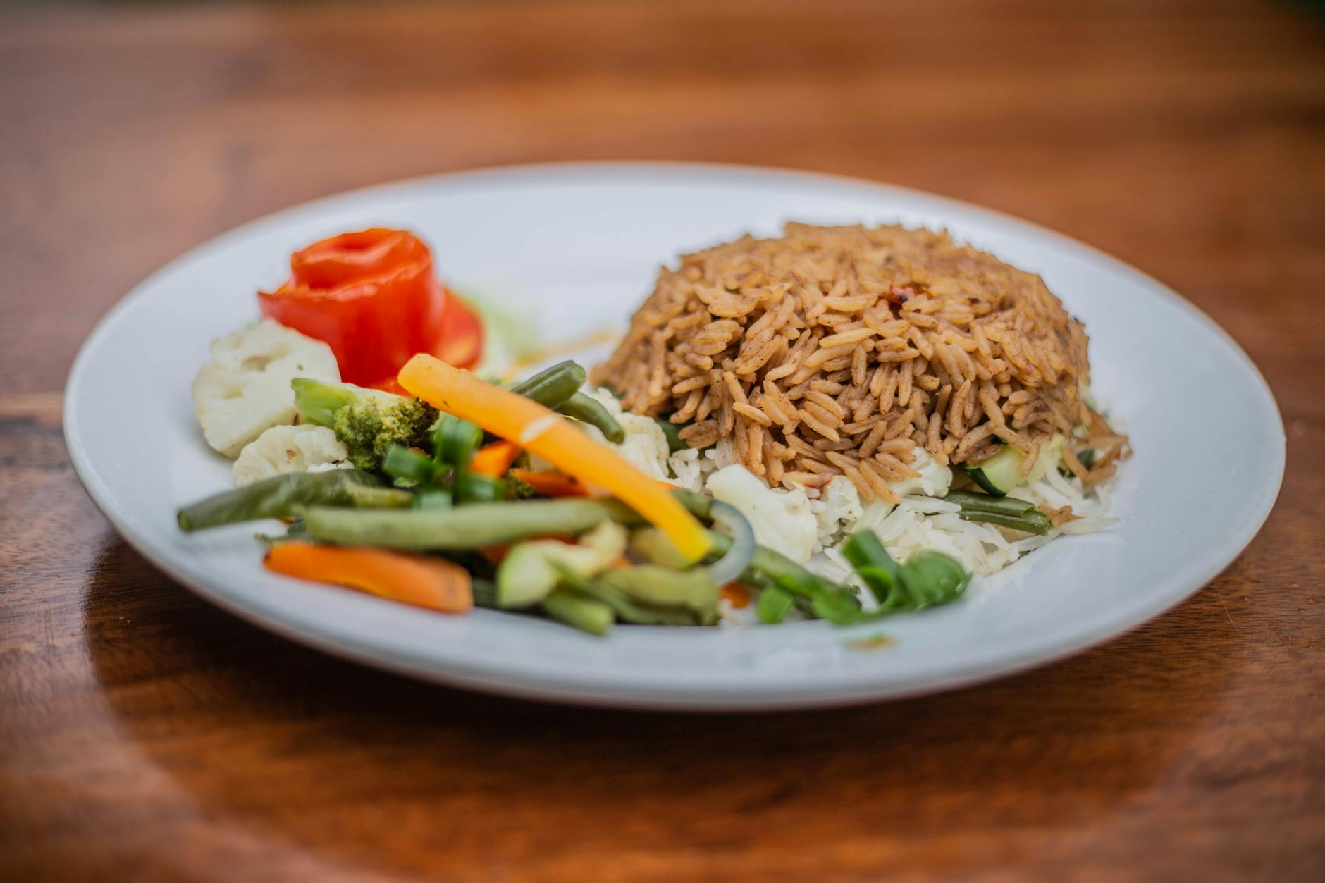 Delicious vegetarian rice dish with mixed vegetables on a white plate, perfect for healthy meals.