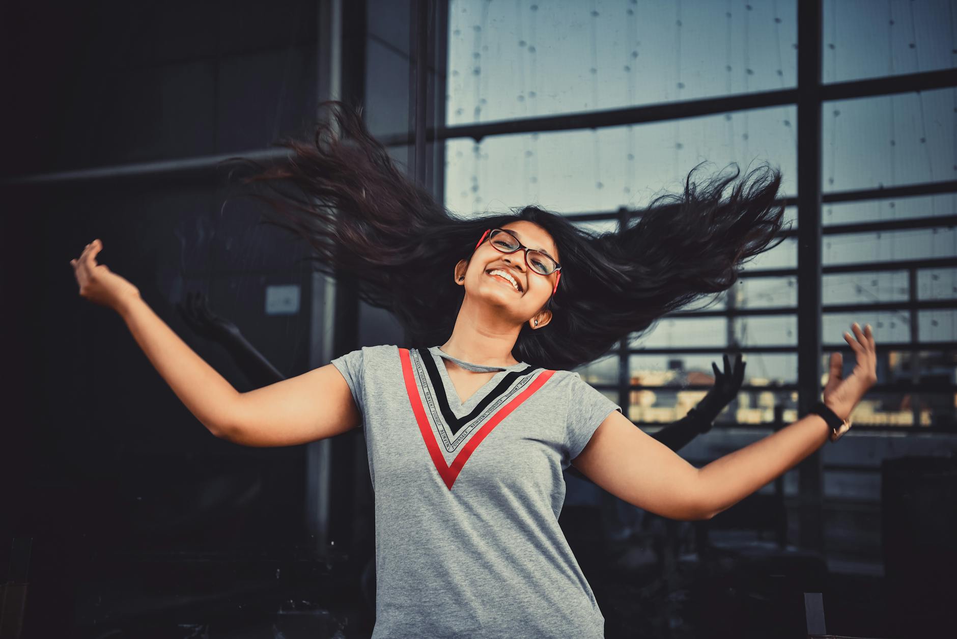 Smiling Indian woman with flowing hair outdoors in Hyderabad, expressing joy and freedom.