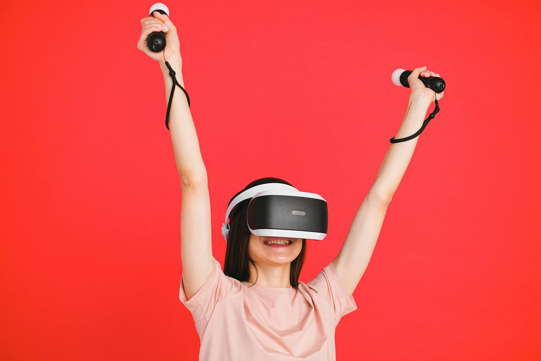 Woman wearing VR headset and holding controllers against vibrant red background.