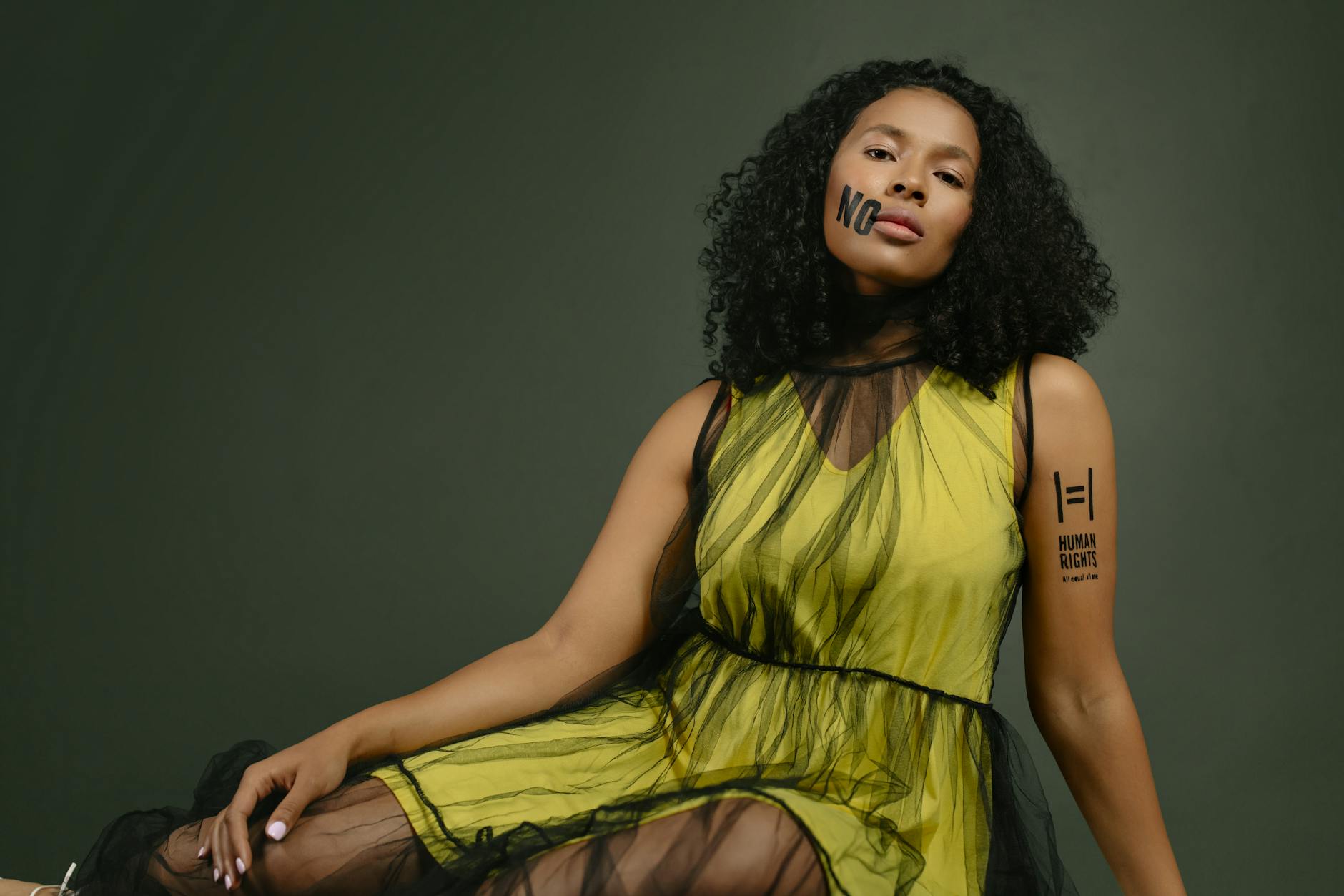 Portrait of an empowered woman with curly hair advocating for human rights in a studio setting.