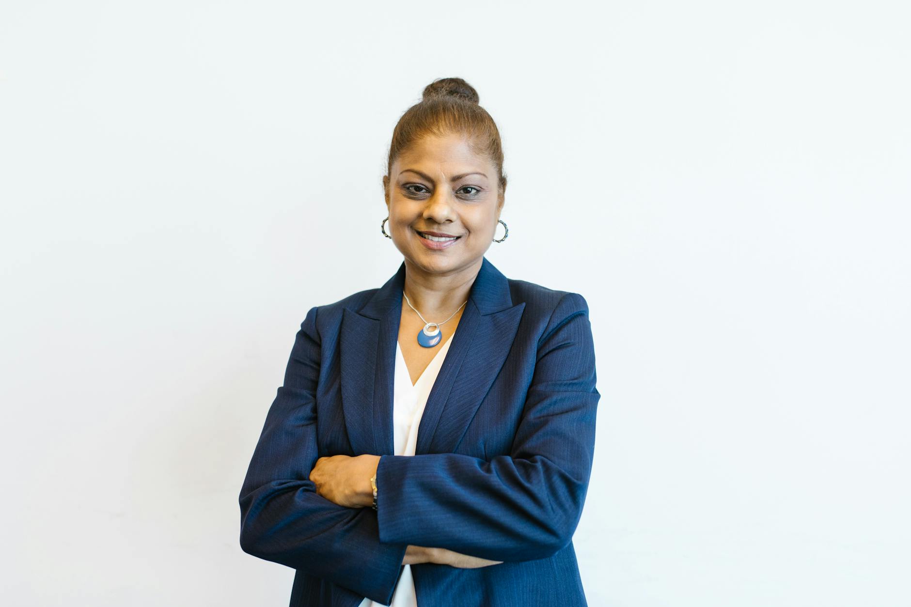 Portrait of a confident businesswoman in professional attire with a friendly smile, arms crossed.