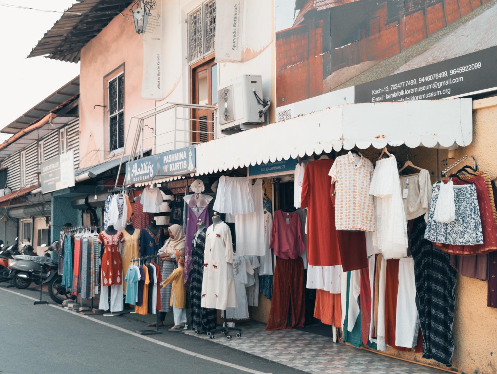Vibrant street market featuring diverse clothing on display in an urban setting.