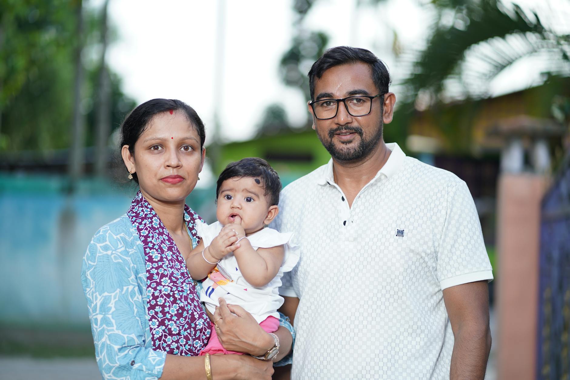 Portrait of a family outdoors with parents holding a baby.