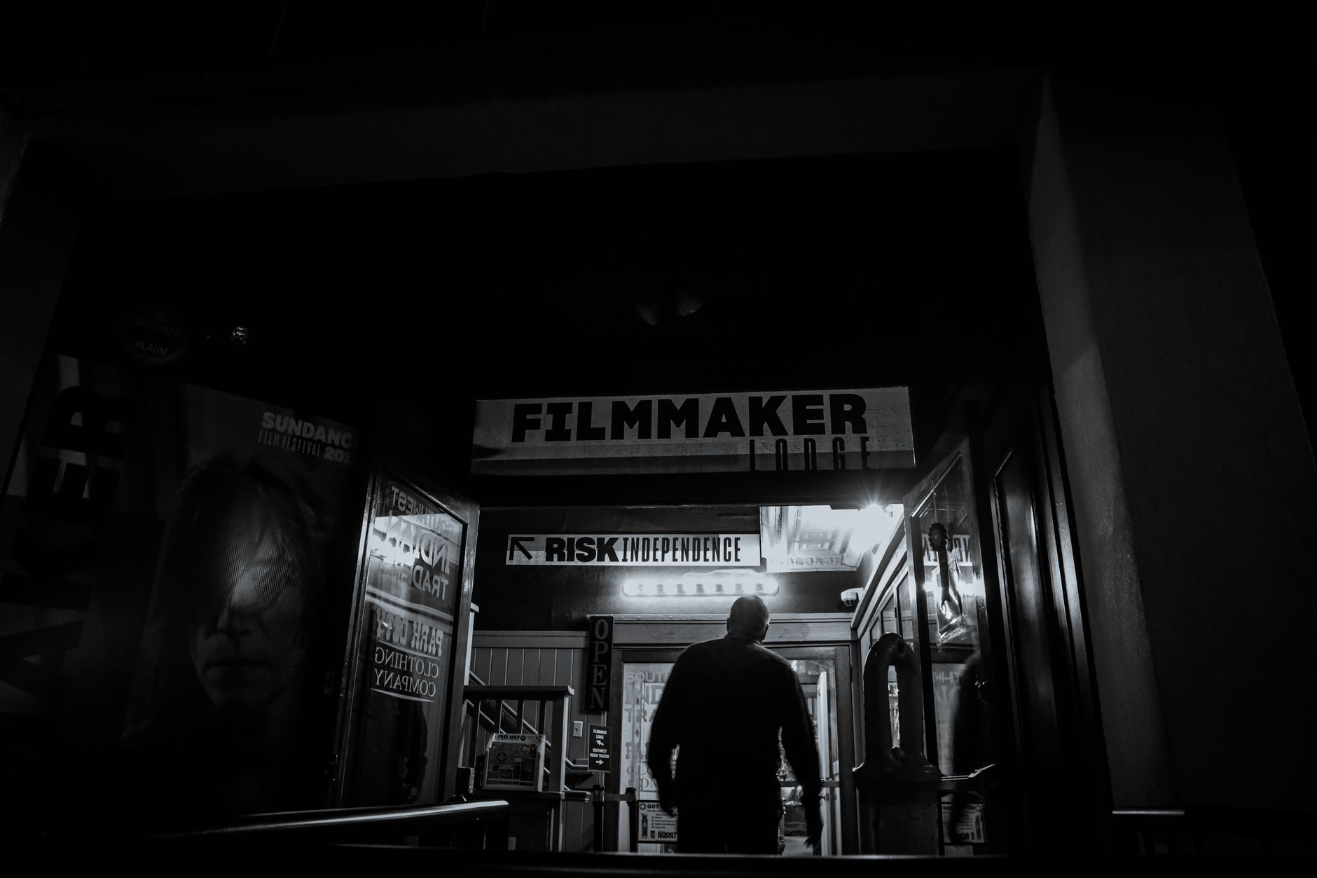 Independent filmmaker entering a dark cinema building at night