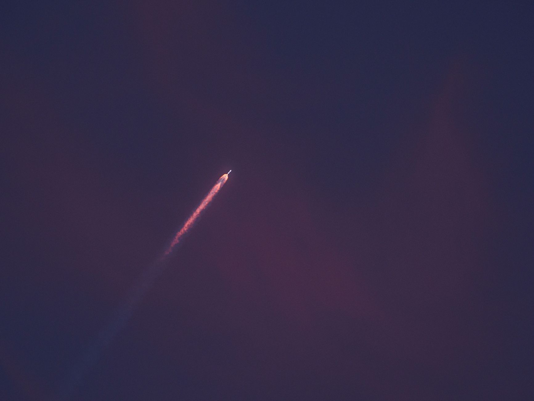 A stunning view of a rocket leaving a fiery trail as it ascends into the night sky.