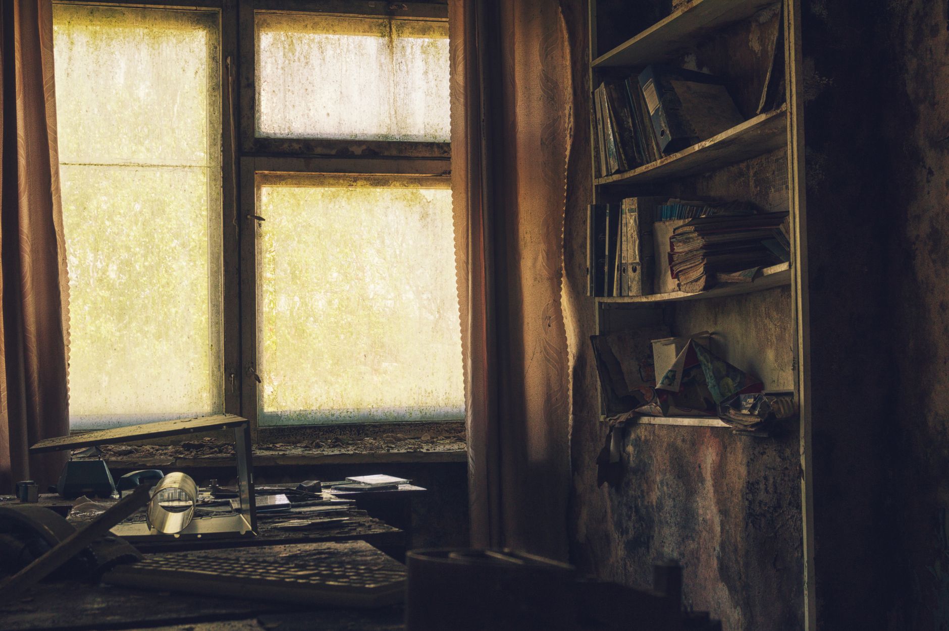 A dimly lit, abandoned office interior with dusty shelves and a yellow-lit window casting shadows.