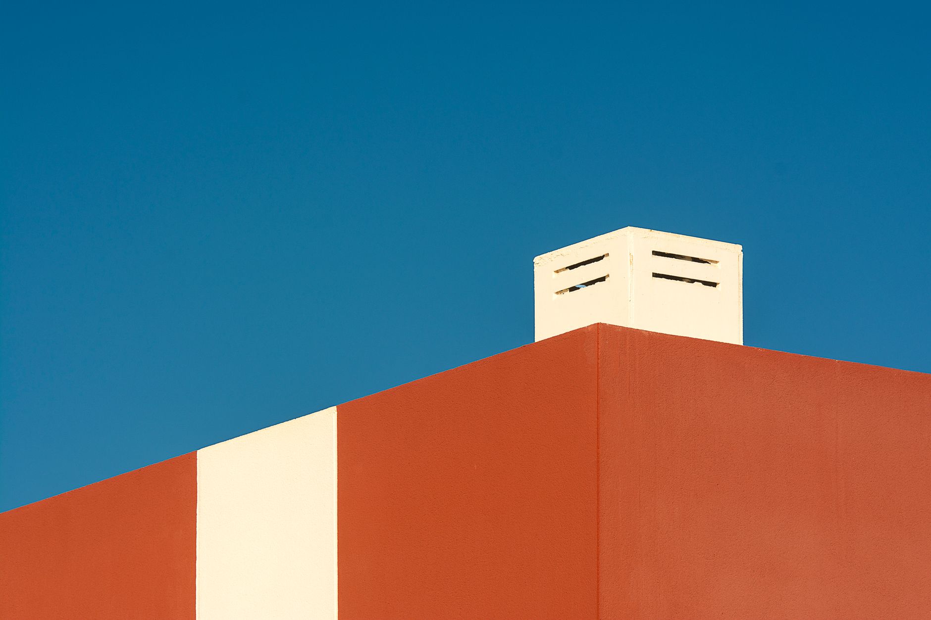 A clean, minimalist view of a building facade against a clear blue sky.